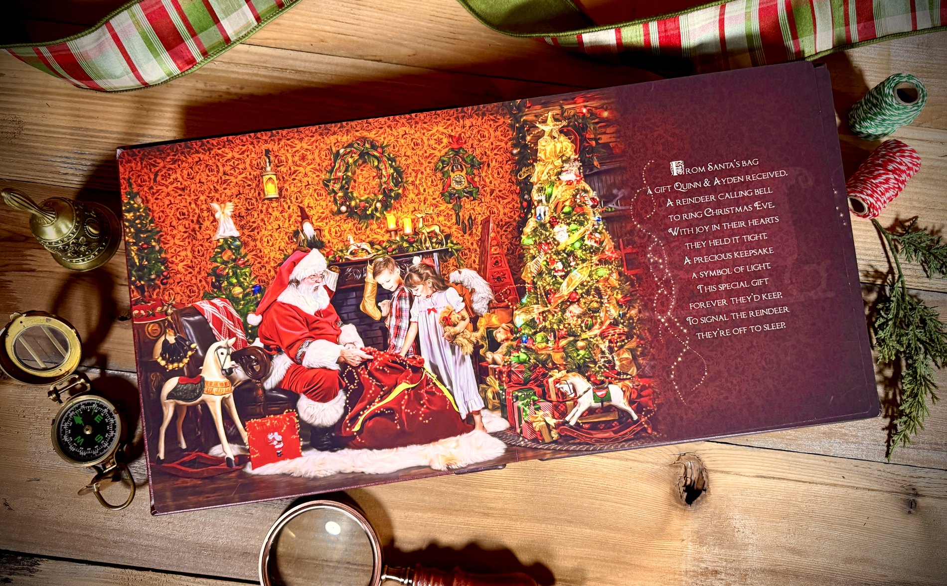 An open keepsake storybook spread — a painted scene of Santa and two children by the fire, beside a verse that begins 'From Santa's bag, a gift Quinn & Ayden received'