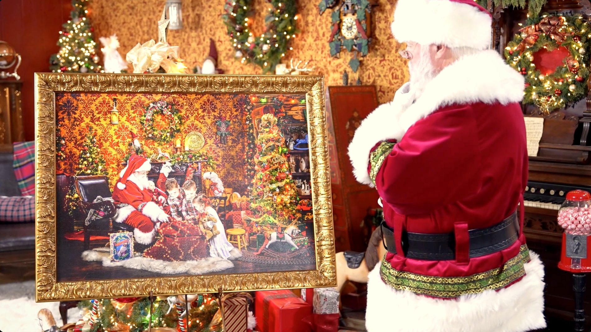 A finished fine-art wall piece of Santa and children, on a gilded easel in the workshop